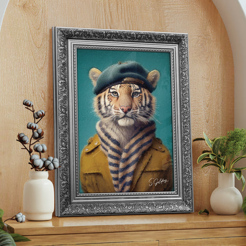 Framed artwork of a tiger wearing a coat and beret in a silver frame on a wooden surface