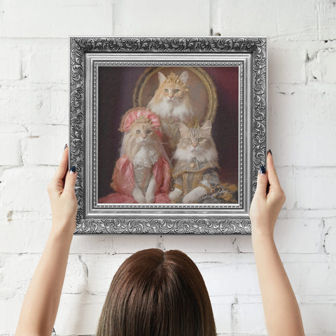 Silver framed artwork of cats in regal attire being hung on wall by a person