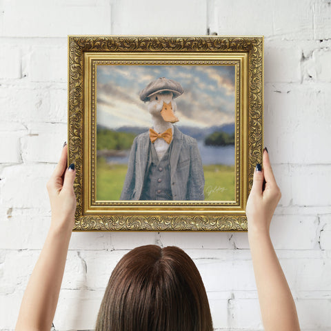 Framed artwork of a duck wearing a suit with a scenic background, displayed in a gold frame being hung on wall